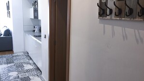 Un couloir doté d’un sol à motifs, d’une porte en bois et d’un porte-manteau mural muni de crochets numérotés de 1 à 4.