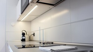 Une cuisine moderne dotée d’un évier en acier inoxydable, d’un plan de travail noir et d’un pare-feu blanc.