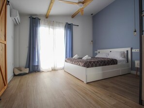 A bedroom with a bed, wooden floor, and a ceiling fan.