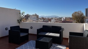 Una terraza en la azotea con mobiliario exterior y vistas a la ciudad.