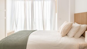 Un dormitorio con una cama, una manta verde y un cabecero de madera.