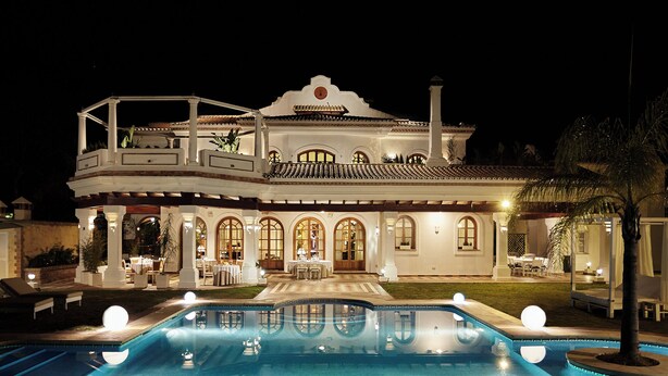 Ein großes, zweistöckiges Haus mit Schwimmbecken davor.
