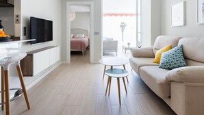 Una sala de estar moderna con un sofá, una mesita redonda y un televisor sobre un mueble bajo.
