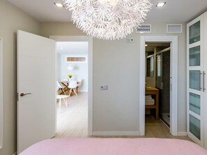 Ein Schlafzimmer mit Bett, einer Tür zu einem Badezimmer und einem Flur mit Essbereich.