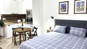 A bedroom with a bed, a nightstand, and two framed pictures on the wall.