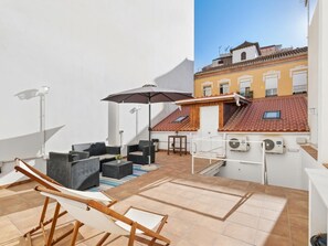 Une terrasse sur le toit, avec des sièges extérieurs, un hamac et une vue sur les bâtiments voisins.