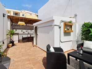 Une terrasse comprenant un espace repas, des sièges d’extérieur et un petit coin cuisine.