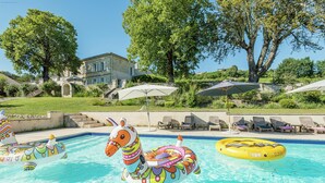 A swimming pool with colorful inflatable boats, lounge chairs, and a building in the background. - Beautiful Stone House near Saint-Émilion and Libourne (Saint-Germain-de-la-Rivière)