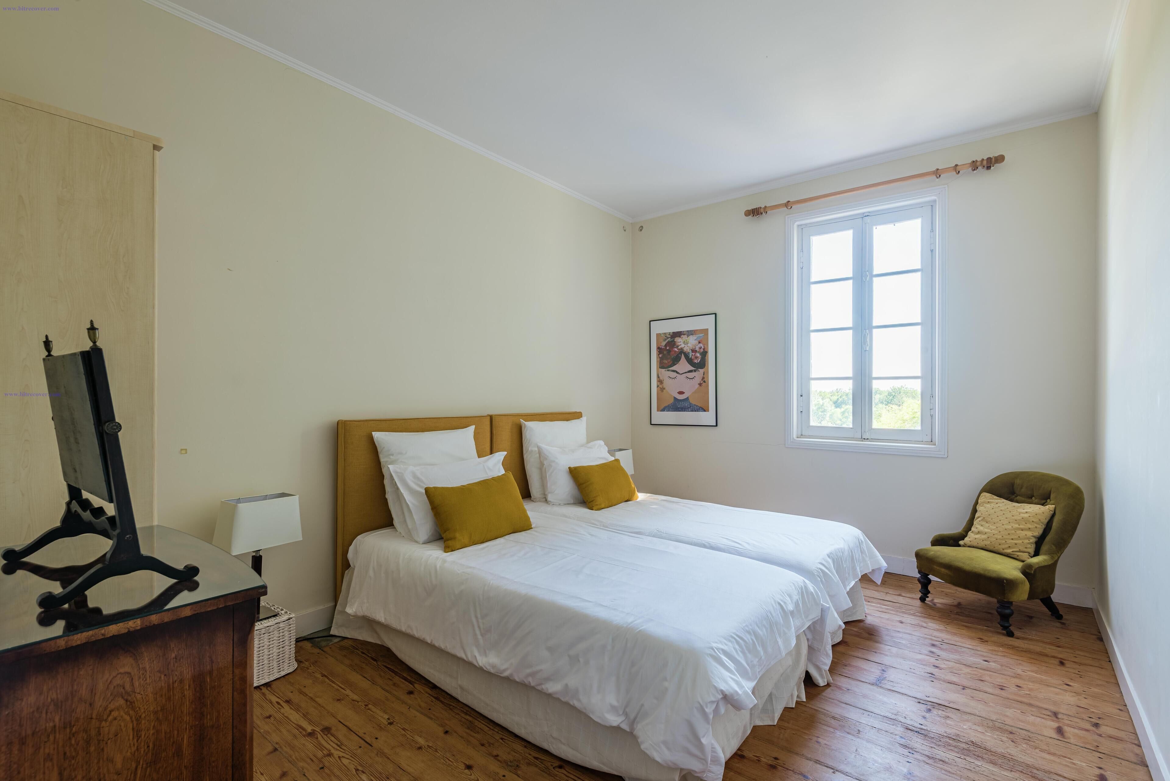 Une chambre avec deux lits, un bureau, une chaise et une fenêtre.