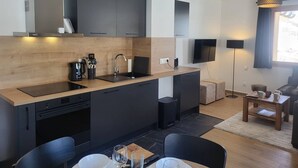 Una cocina moderna con armarios oscuros, encimera de madera y estufa integrada.