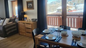 Una sala de estar acogedora con un sofá, una mesita de madera y un comedor con mesa preparada para cuatro.