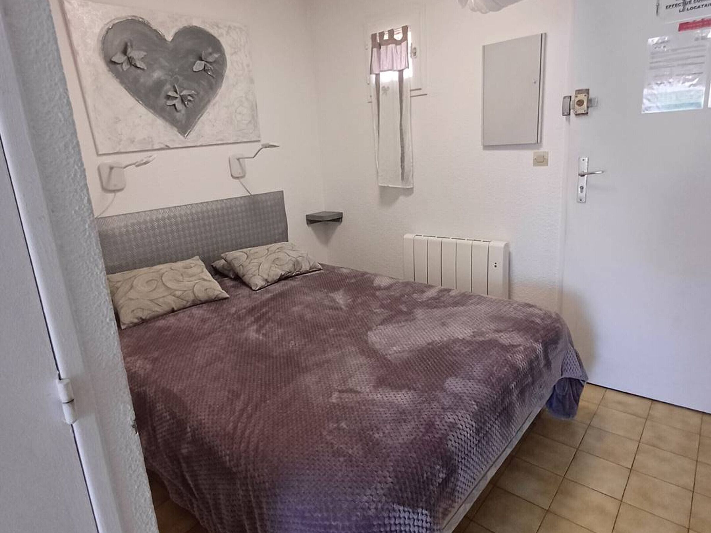 Un dormitorio con cama, radiador, espejo y un adorno en la pared.