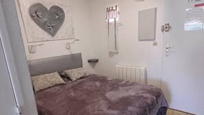 A bedroom with a bed, a radiator, a mirror, and a wall decoration.