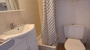 A bathroom with a white sink, a toilet, and a shower with a patterned curtain.
