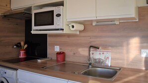 A compact kitchen with a microwave, sink, and a washing machine. - Cozy 2-Room Apartment in Bolquère, Near Shops and Skiing (Bolquère-Superbolquère)