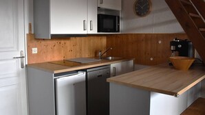 A compact kitchen with white cabinets, a microwave, a sink, and a wooden countertop. - Cozy 2-room apartment with garden in Bolquère (Bolquère-Pyrénées 2000)