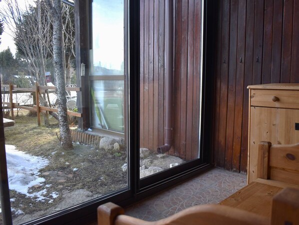 Una habitación con un ventanal grande, paredes de madera y un pequeño armario de madera.