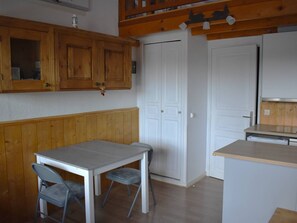 Compact kitchen area with a dining table for two, featuring a white countertop and cabinetry.