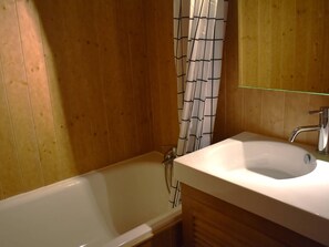 Bathroom features a bathtub, sink, and shower, along with a mirror and storage.