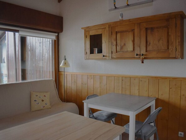 Cozy guest room with a single bed, dining table, and wooden cabinet.