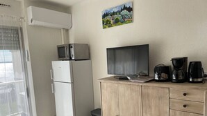 A compact kitchenette with a refrigerator, microwave, and a flat-screen TV. - Comfortable Studio with Loggia in Balaruc-les-Bains (Balaruc-les-Bains)