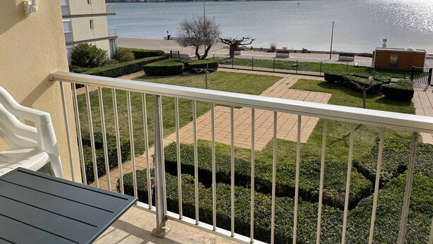 A balcony with a view of a landscaped garden and a body of water. - Comfortable Studio with Loggia in Balaruc-les-Bains (Balaruc-les-Bains)