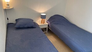A small, single-room accommodation with two single beds, a bedside table with a lamp, and a power outlet. - Comfortable Studio with Loggia in Balaruc-les-Bains (Balaruc-les-Bains)
