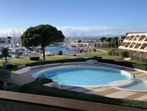 Una piscina con vistas a un puerto deportivo y un edificio de diseño moderno.