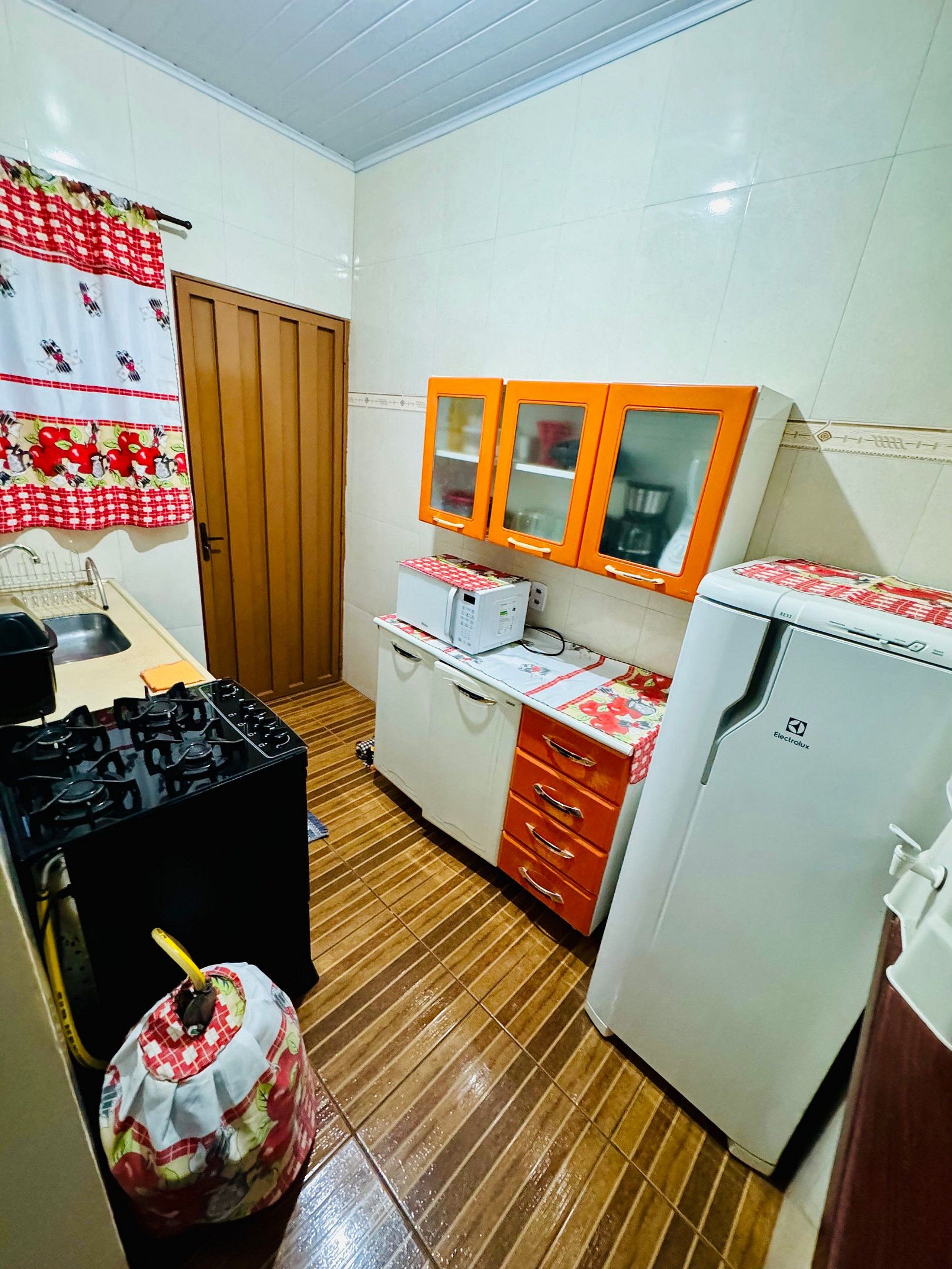 A compact kitchen with a gas stove, a refrigerator, and a microwave.