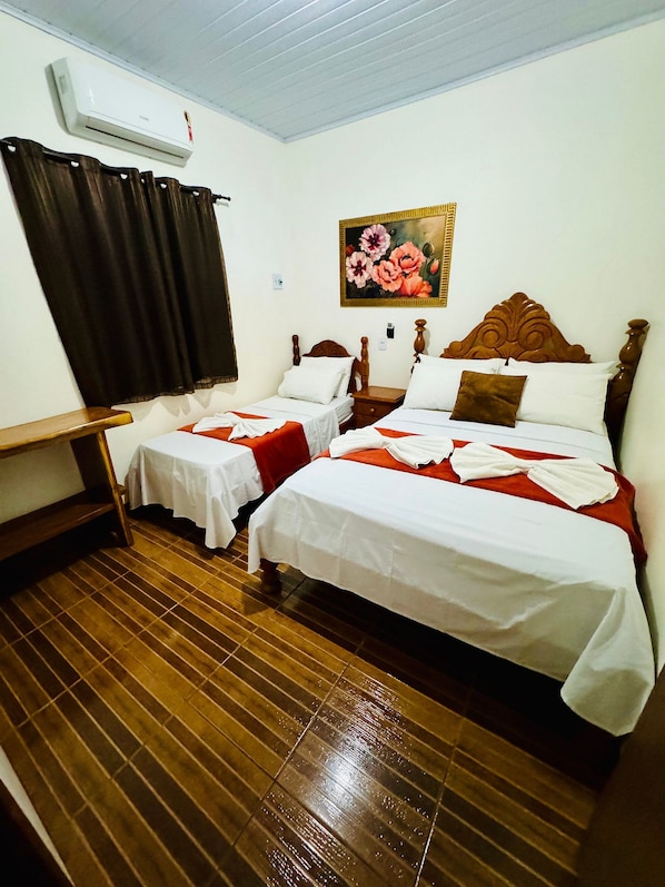 A hotel room with two single beds, a wooden headboard, a painting of flowers, a wooden table, and a window with curtains. - Casa Flor do Ipê Homes (Nobres)