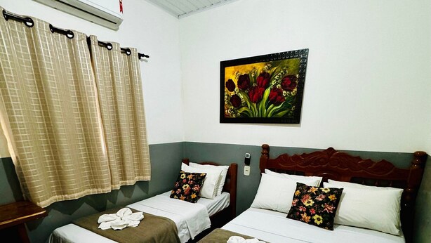 A hotel room with two beds, a painting, an air conditioner, and a curtain. - Casa Flor do Ipê Homes (Nobres)