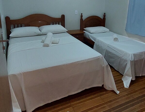 A hotel room with two single beds, each with a wooden headboard, white linens, and a neatly rolled towel. - Casa Flor do Ipê Homes (Nobres)