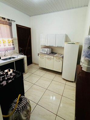 A kitchen with white cabinets, a microwave, a refrigerator, and a stove. - Casa Flor do Ipê Homes (Nobres)