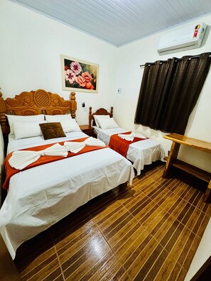 A hotel room with two beds, wooden headboards, a painting of flowers, a window with curtains, and a wooden floor. - Casa Flor do Ipê Homes (Nobres)