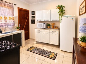 A kitchen with white cabinets, a microwave, a refrigerator, and a sink. - Casa Flor do Ipê Homes (Nobres)