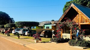 A rustic building with a sloped roof, surrounded by parked cars and potted plants. - Casa Flor do Ipê Homes (Nobres)