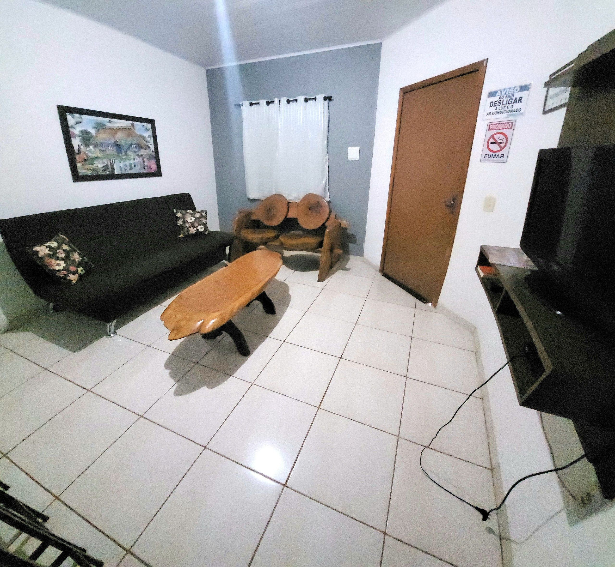 A living room with a sofa, a wooden bench, a television, and a door with a sign.