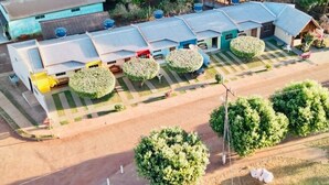 An aerial view of a residential area with multiple houses, a central building with a blue roof, and well-maintained gardens. - Casa Flor do Ipê Homes (Nobres)