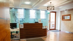 Un comptoir d’accueil avec une cloison en verre, un lustre et une enseigne indiquant les appartements CASARTELLI.
