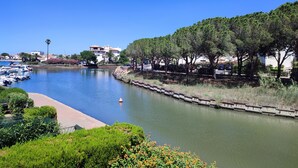 A marina with boats docked, a river, and a row of trees along the riverbank. - Studio at the marinas (Saint-Cyprien)
