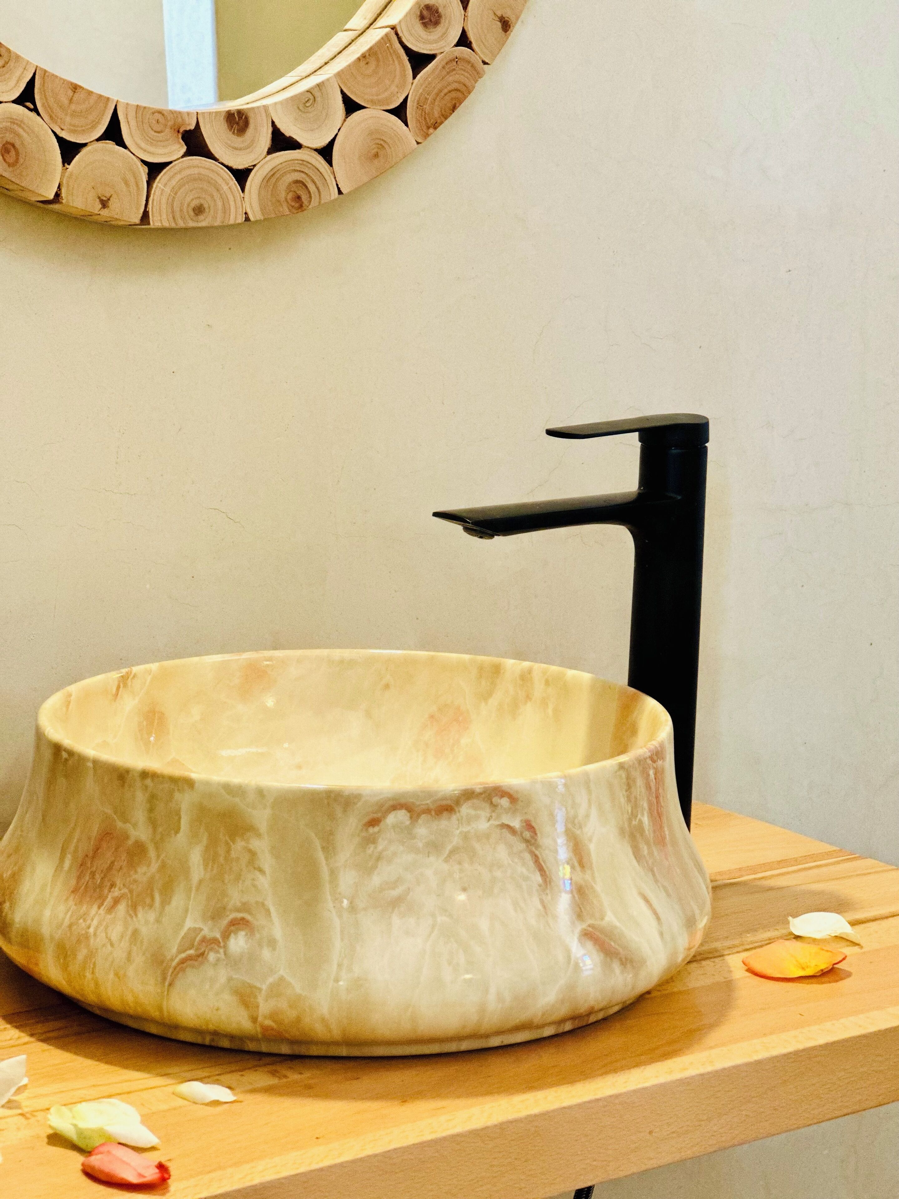 A bathroom with a round basin, a black faucet, and a wooden wall panel.
