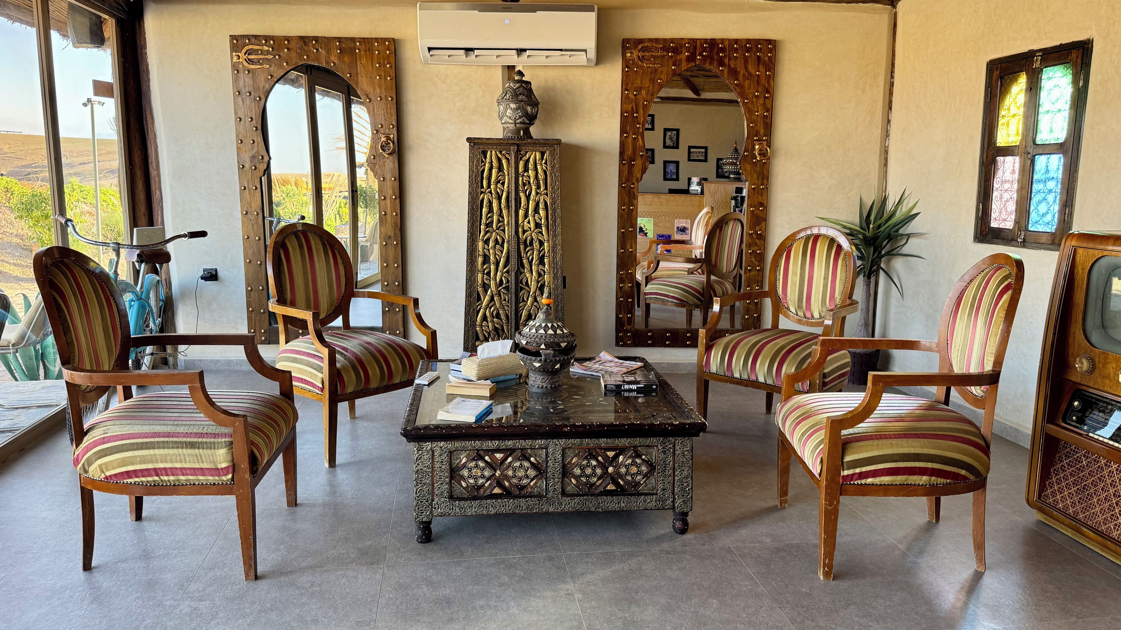 Una habitación con cuatro sillas a rayas, una mesa de centro y un espejo decorativo.