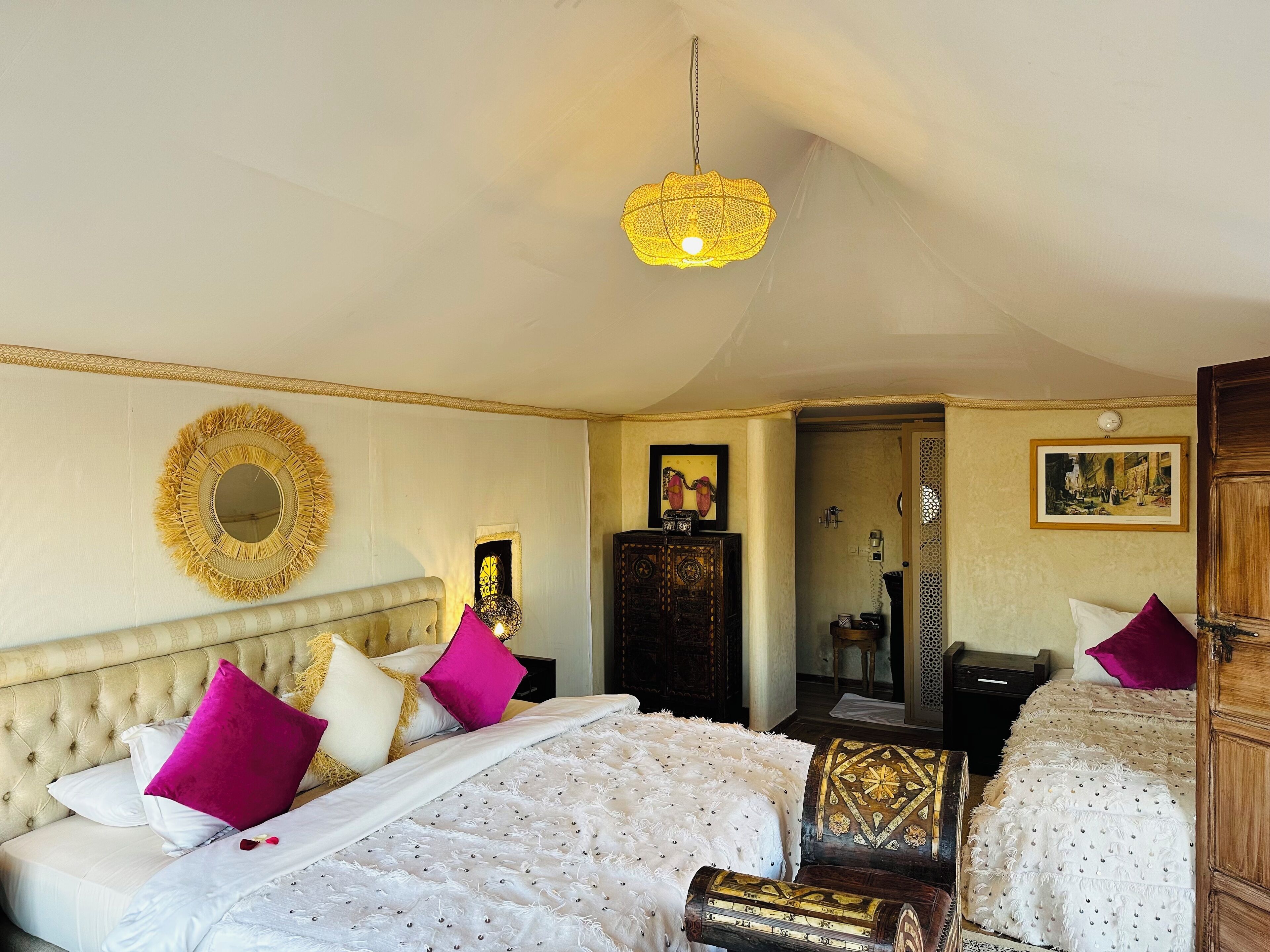 Quarto de hotel com duas camas, um espelho grande e um candelabro.