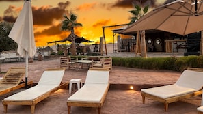 A rooftop lounge area with wooden lounge chairs, a table, and umbrellas. - Yes We Camps Luxury lodge & spa (Agafay)