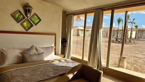 Ein geräumiges Schlafzimmer mit einem großen Bett, Blick auf eine Wüstenlandschaft und einer traditionellen Laterne.
