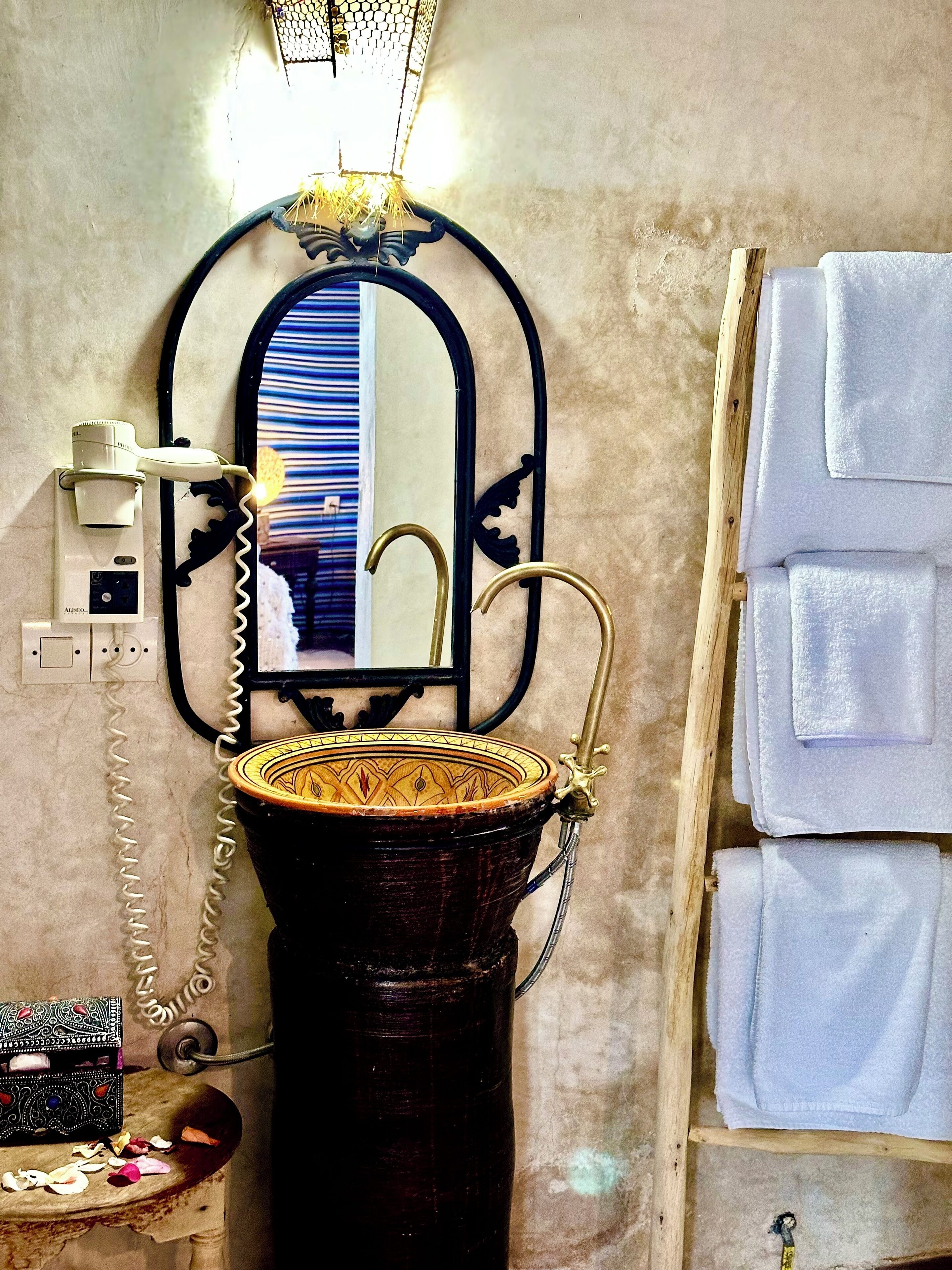 Une salle de bain avec un lavabo d’époque, un miroir doté d’un cadre décoratif et un porte-serviettes.