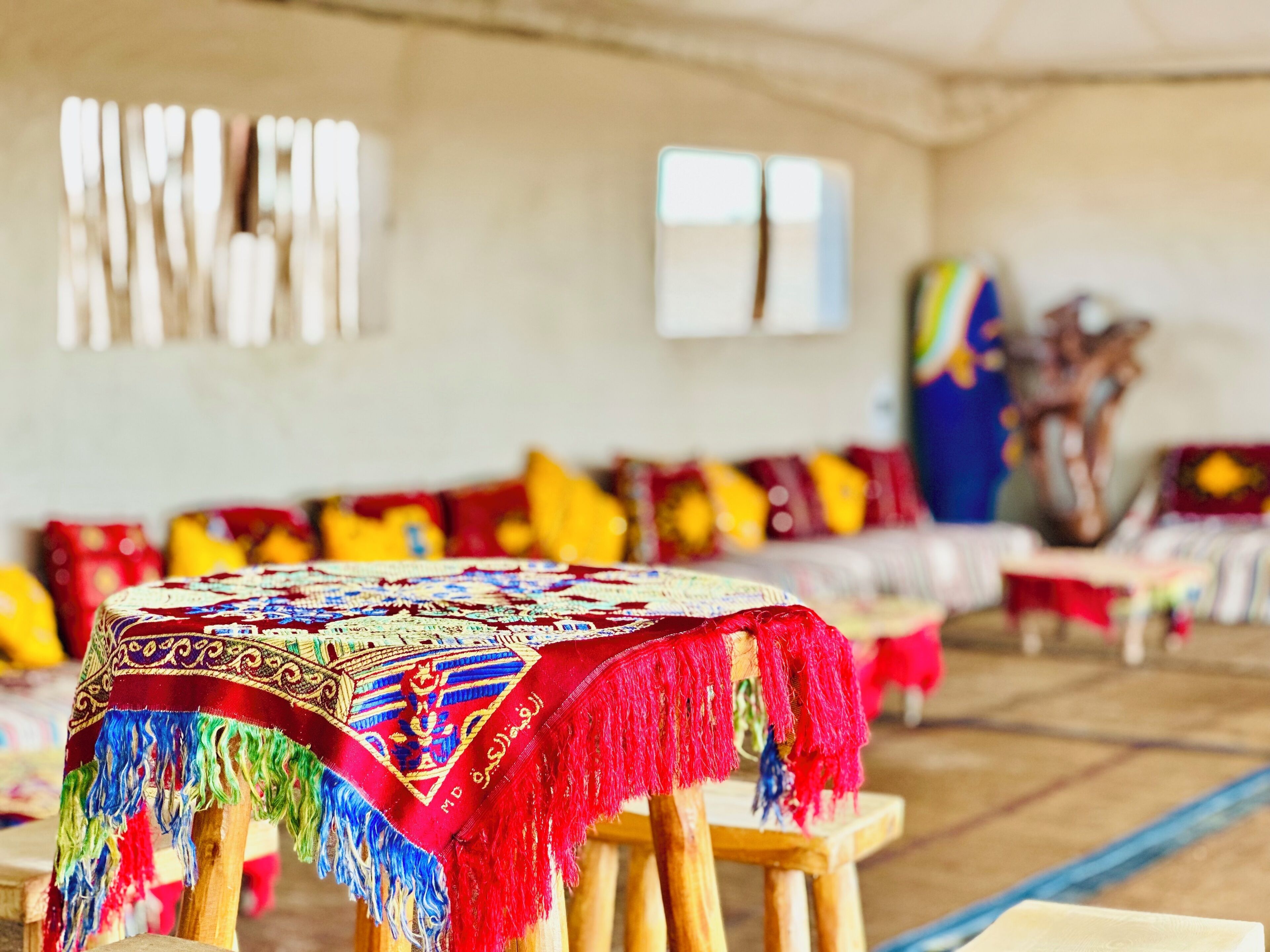 A room with a traditional patterned tablecloth, wooden furniture, and colorful cushions.