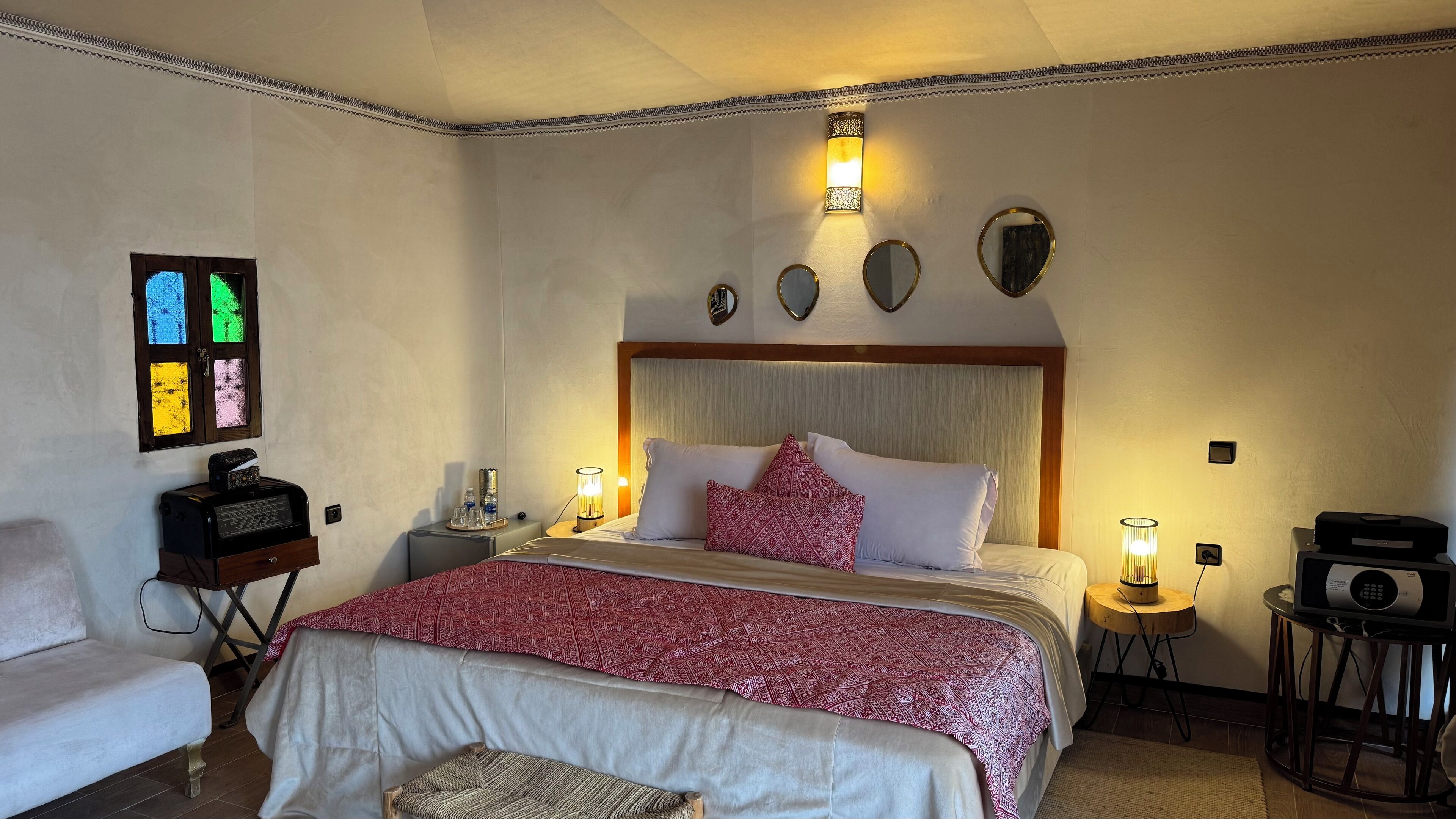 Une chambre bien aménagée, dotée d’un grand lit, de lampes de chevet, d’une petite table, d’une chaise et d’un téléviseur fixé au mur.