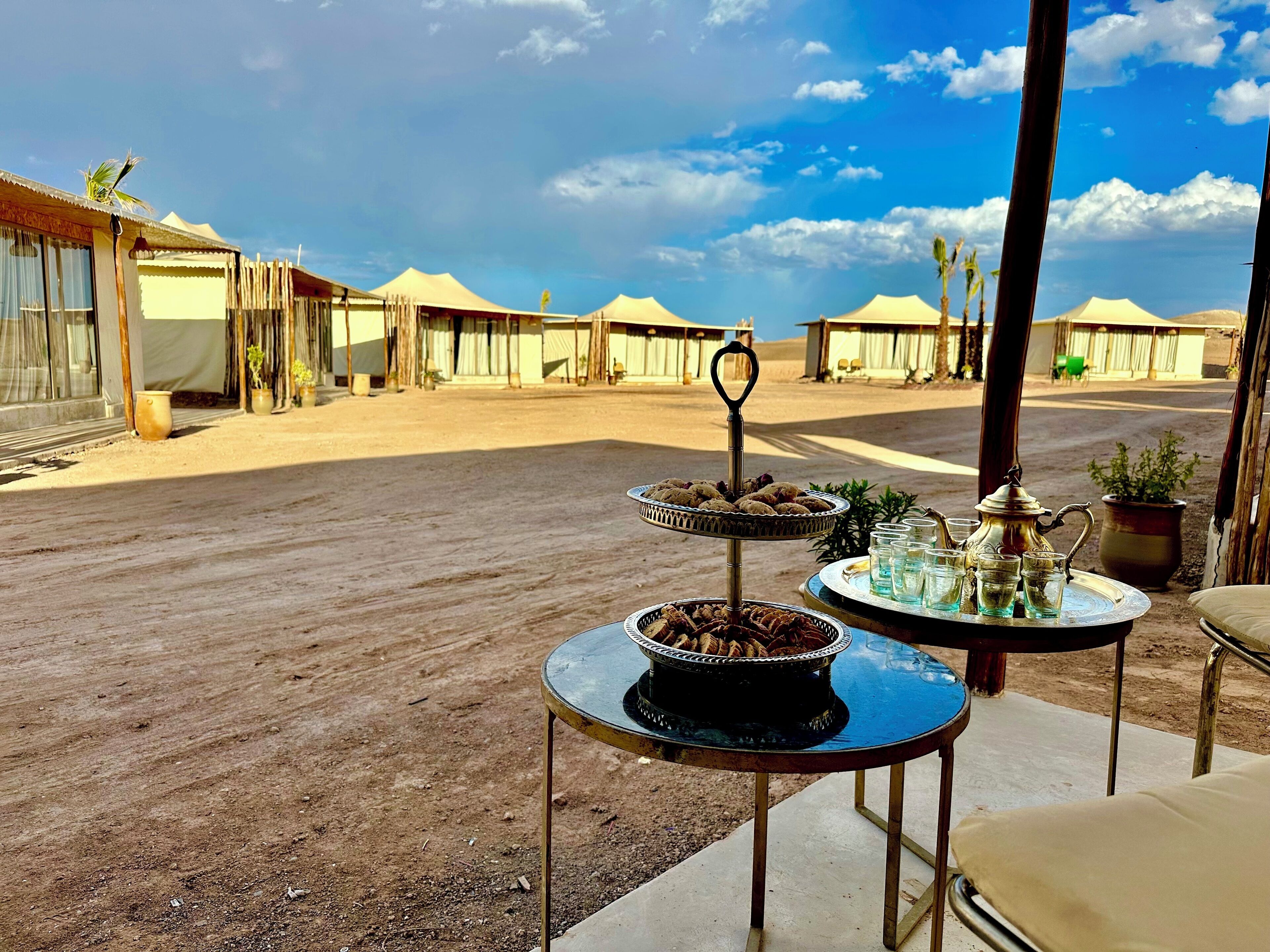 A desert setting with tents and a table with food and drinks.