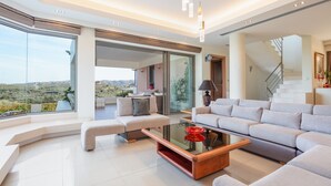 A spacious living room with a glass coffee table, a sofa set, and a view of the outdoors. - Villa Anastasia - Private Pool Panoramic Views (Platanias)